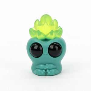 A turquoise resin figure with large black eyes and a yellow-green Echeveria Archie atop its head, designed by Chris Ryniak.