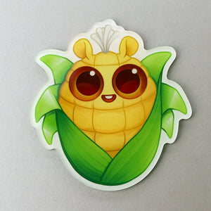 An adorable "Sweet Corn" Acrylic Magnet featuring an animated corn cob character from Thimblestump Hollow, with wide, sparkling eyes, green leaves forming a protective layer, and a single leaf sprout on top, giving. Brand: Bindlewood Shop
