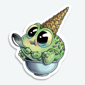 The Sprinkle Frog Sticker (3-inch) from Bindlewood Shop features a cute green frog with big eyes, holding a spoon in a bowl, topped with colorful sprinkles and an ice cream cone—perfect for fans of Chris Ryjniak’s whimsical art style.