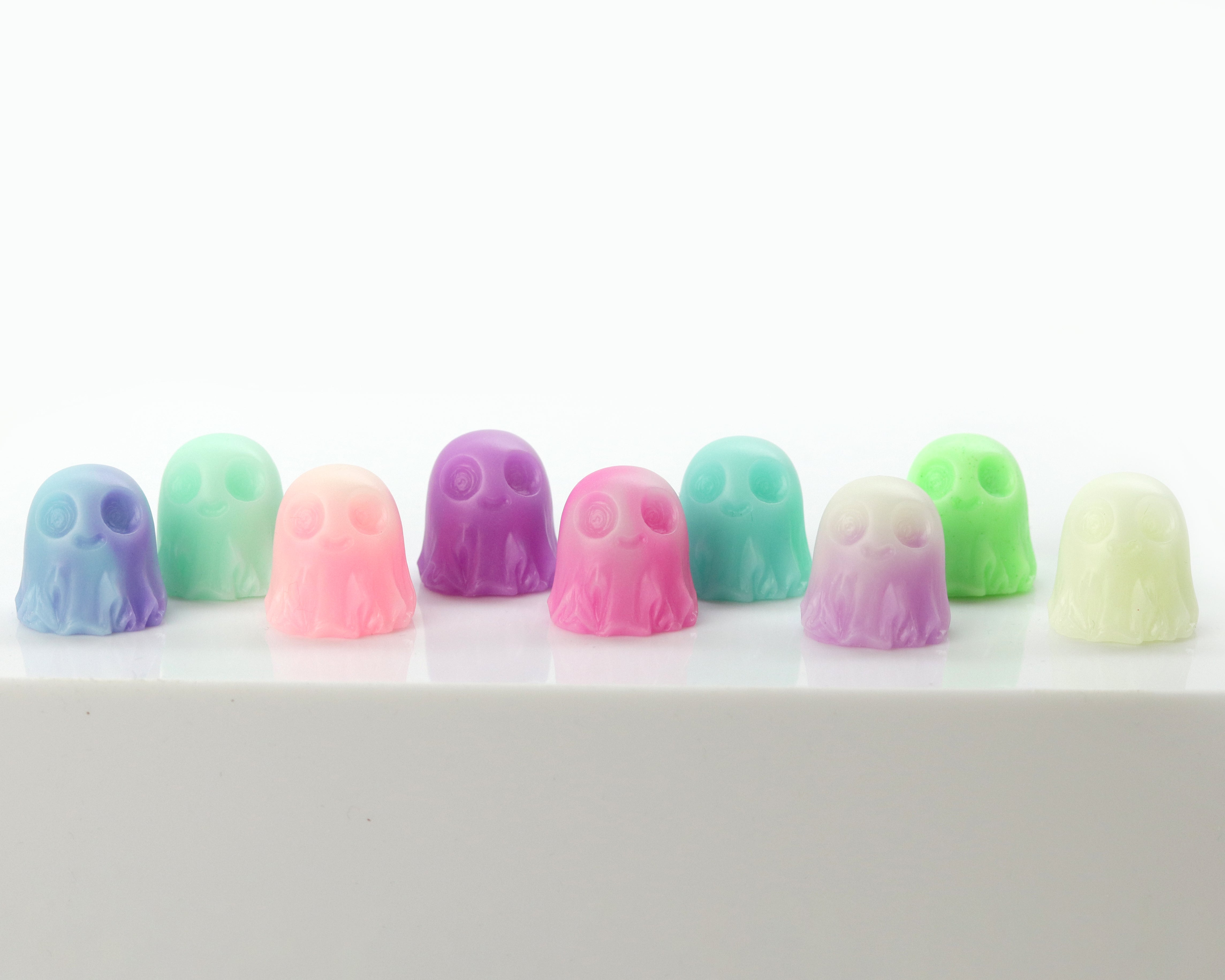 A pair of charming Giddy Ghost keycaps from Bindlewood Shop’s Giddy Ghost Glow 2-pack, inspired by Chris Ryniak’s whimsical designs, are displayed on a white surface against a plain background. Crafted in colorful pastel shades, these delightful ghosts even glow in the dark, bringing a playful and unique accent to any keyboard setup.