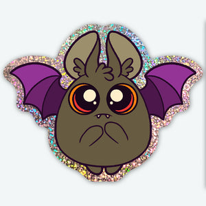 The Bindlewood Shop Dark Glitter Bat Sticker (3-inch) features a round cartoon bat with orange eyes, purple wings, tiny fangs, and a glittery background—perfect as a waterproof vinyl sticker for any surface!.