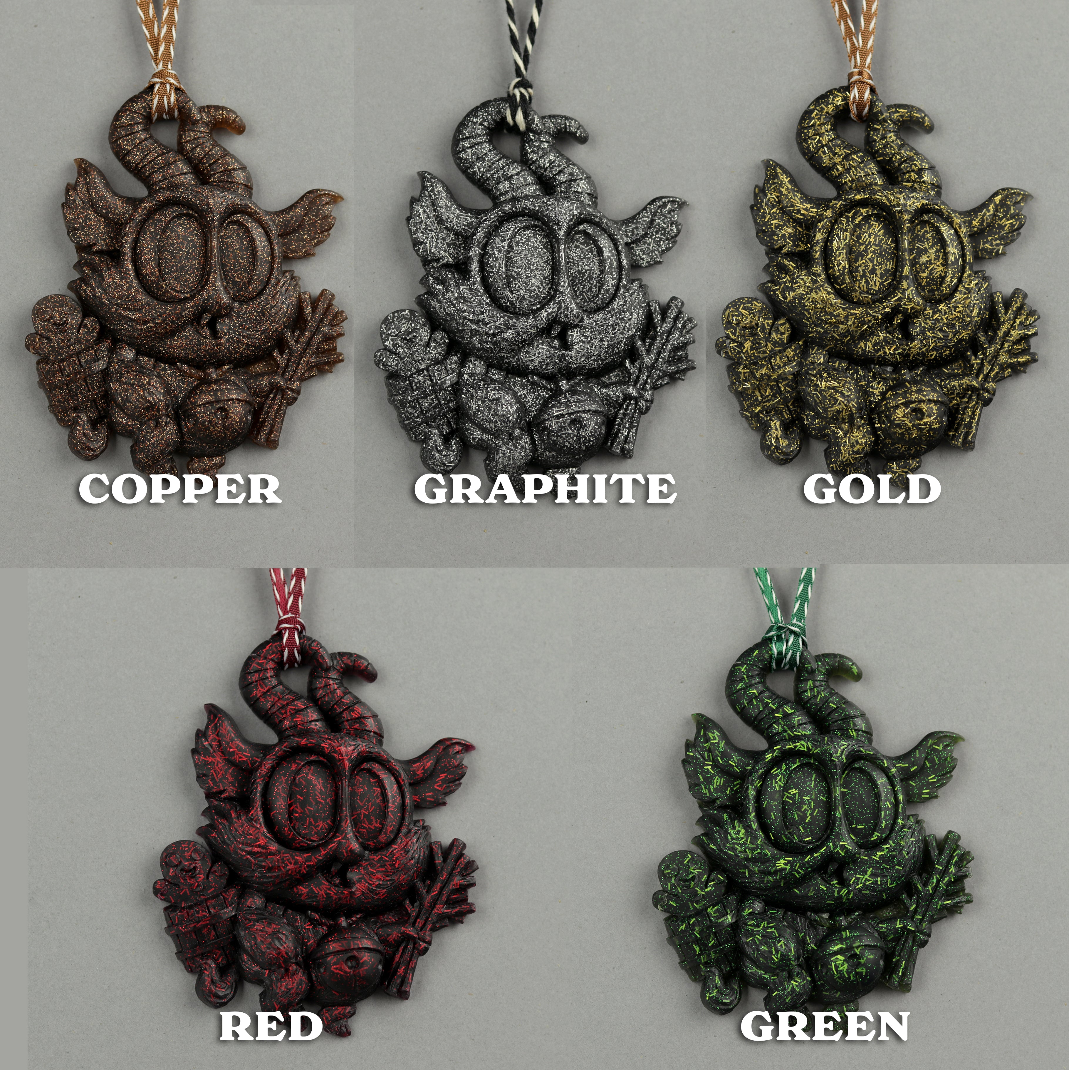 Five Glitter Krampus Ornaments by Bindlewood Shop—sculpted pendants in copper, graphite, gold, red, and green—hang on cords against a neutral background with color labels shown below or beside each ornament.