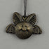 A bronze-colored Painted Mini Ornament shaped like a smiling bat with large ears and outstretched wings from Bindlewood Shop hangs on a black cord against a plain gray background.