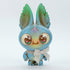 The Blue Kangorumple from Bindlewood Shop is an adorable, small figurine featuring a large head and big, round eyes. Hand-painted in shades of blue and green, it boasts big bunny-like ears with small leaf shapes at their tips. To complete the look, it wears a charming white bow around its neck, and its cheerful facial expression adds to its endearing charm.