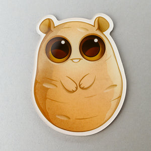 An adorable cartoon hamster sticker with big, glossy eyes looking up, giving an expression of innocence and curiosity, designed by Amanda Spayd for Thimblestump Hollow "Lucky Potato" Acrylic Magnet from Bindlewood Shop.