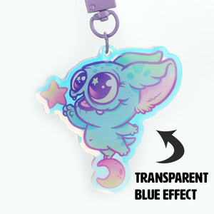 A vibrant and whimsical keychain featuring a colorful, cartoon-like creature from Thimblestump Hollow with large eyes and wings, holding the "Starcatcher" Rainbow Acrylic Charm from Bindlewood Shop with a special transparent blue effect.