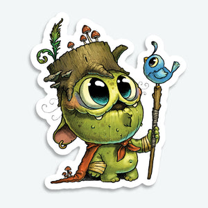 The Wood Wizard Sticker (3-inch) from Bindlewood Shop features a cute green creature with large eyes, a tree stump hat with mushrooms, red scarf, and staff topped by a blue bird. Durable matte vinyl finish.