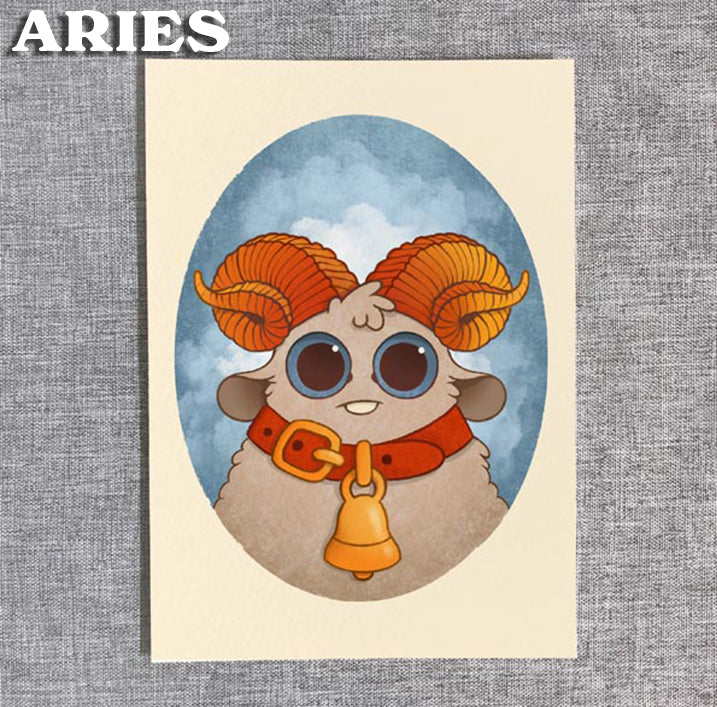 The Zodiac Prints by Amanda Louise Spayd from Bindlewood Shop feature a cute cartoon sheep with orange horns, big eyes, and a red-collared gold bell against a blue oval background and "ARIES" in bold at the top left.