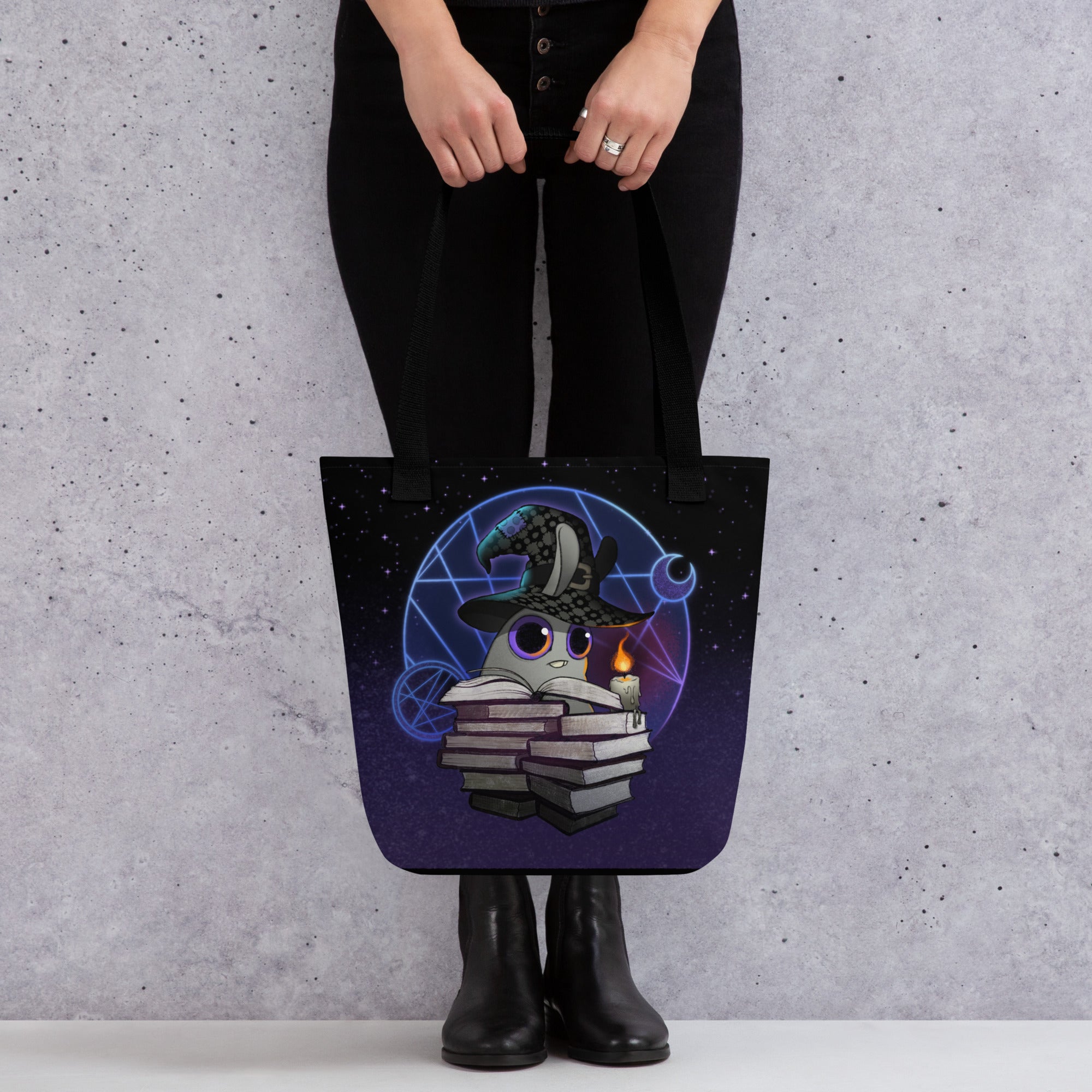 A person in black pants and boots holds the Mystical Witchbunny Tote by Bindlewood Shop, featuring a cute cat in a wizard hat with magical details—ideal for fans of Amanda Louise Spayd or the Witchbunny bag series.