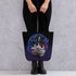 A person in black pants and boots holds the Mystical Witchbunny Tote by Bindlewood Shop, featuring a cute cat in a wizard hat with magical details—ideal for fans of Amanda Louise Spayd or the Witchbunny bag series.