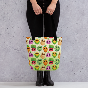 Colorful avocados with playful expressions adorn the Bindlewood Shop All the Veggies Tote held by a person standing against a textured grey background.
