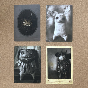 A collection of four Dust Bunnies Cabinet Card Sets by Bindlewood Shop, each displaying an imaginative and eerie creature with anthropomorphic features, set against antique photos that evoke a sense of dark fairy tale mystique.