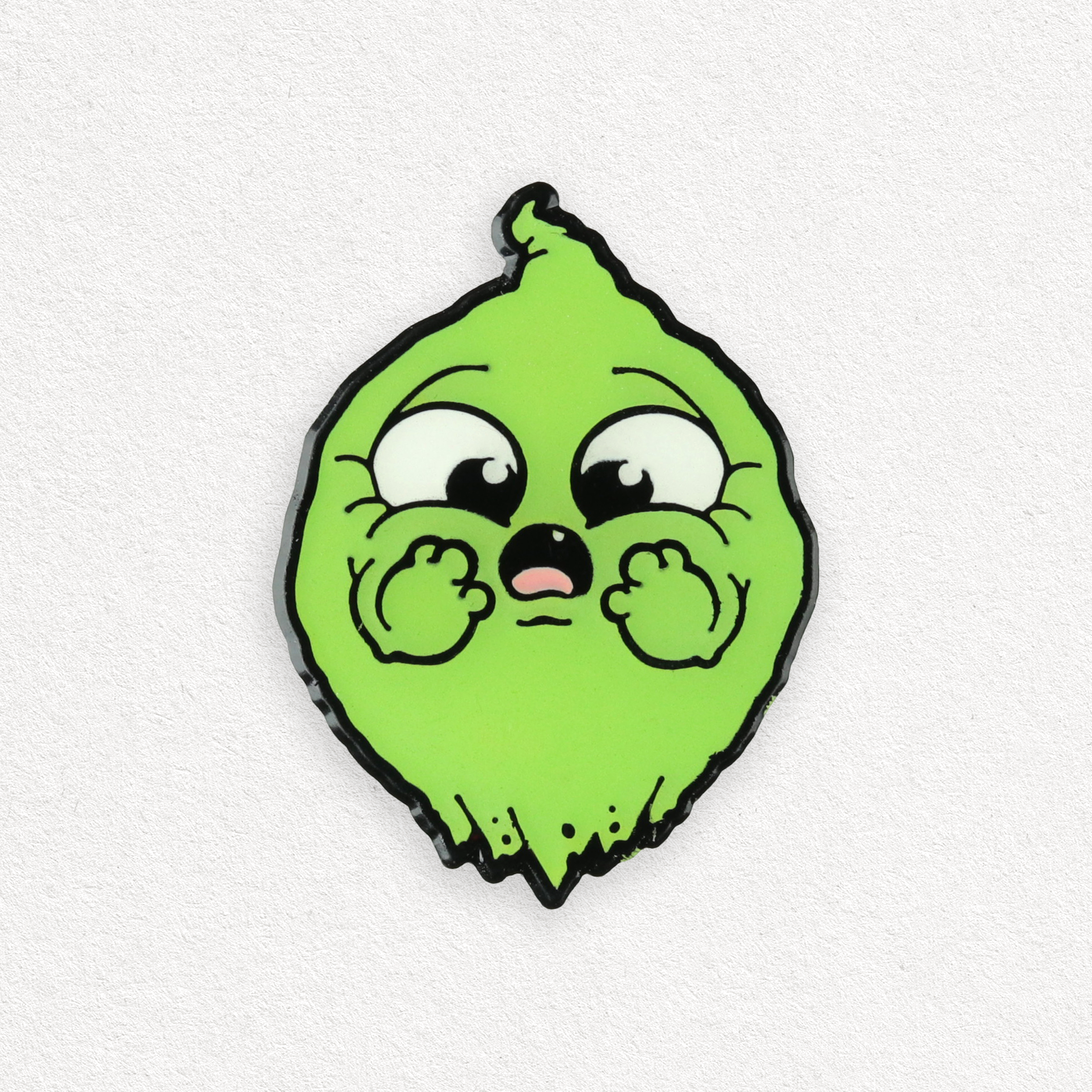 A cartoon-style green lime character with big, expressive eyes and a surprised face, hands on cheeks—reminiscent of the O.M.Ghost Pin (Glows in the Dark!) from Bindlewood Shop. Background is plain white.