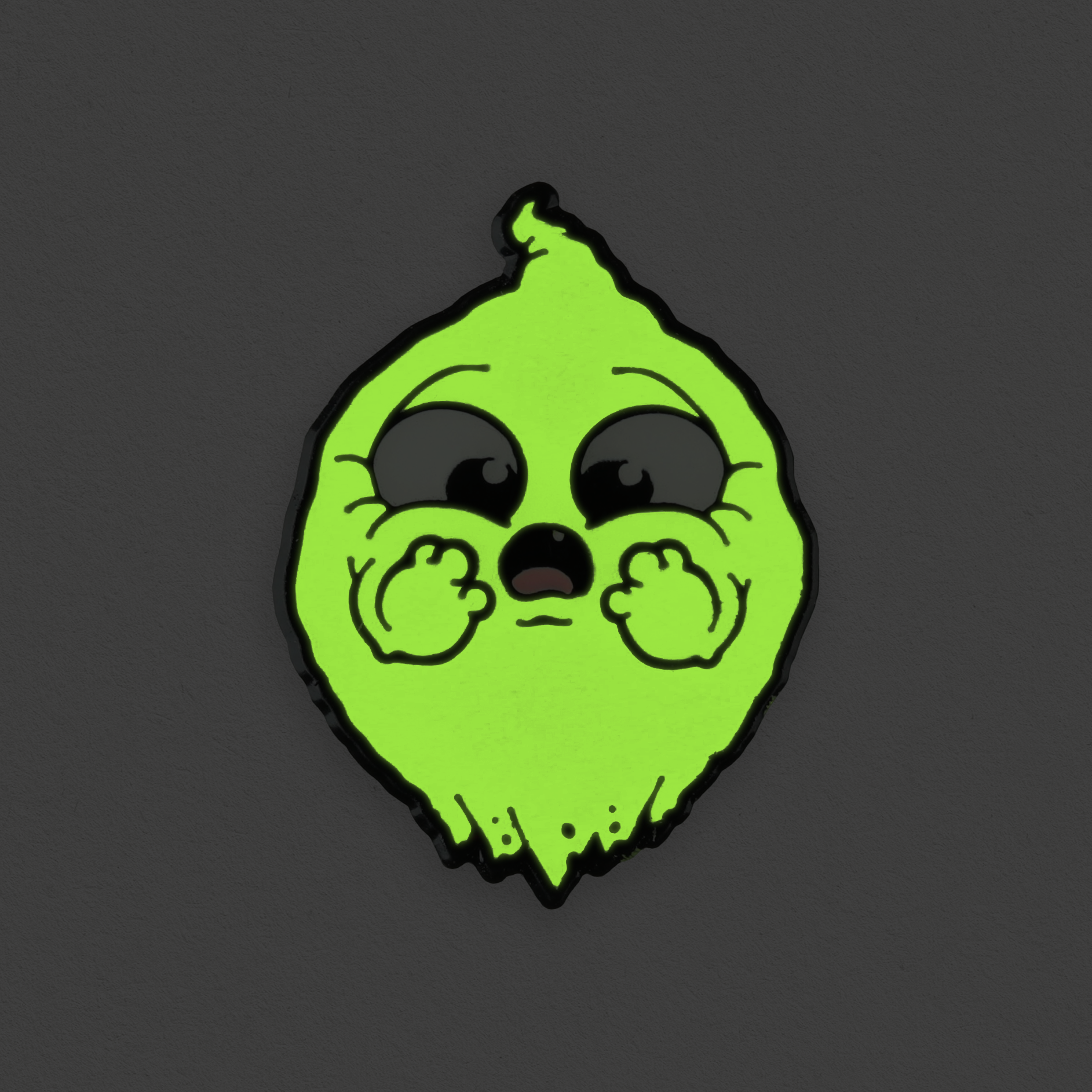 The O.M.Ghost Pin by Bindlewood Shop features a cute, cartoonish green lemon with big shiny black eyes and chubby cheeks, holding its tiny hands to its face against a dark gray background—and it glows in the dark!.