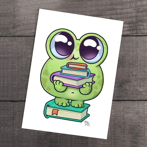 A cartoon illustration of a cute green frog from Thimblestump Hollow with large eyes clutching a stack of colorful books, looking eager to read or learn, "Read A Bit" Print by Chris Ryniak, set against a gray wooden background.