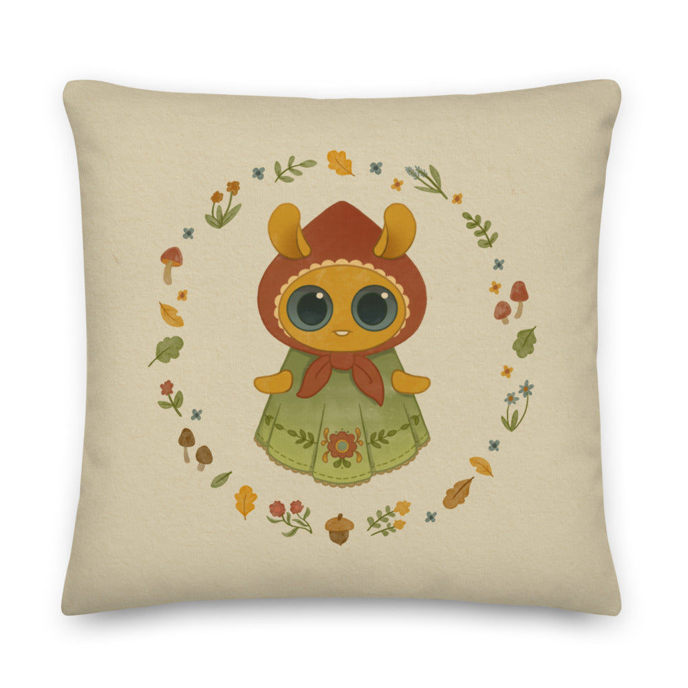 The Bindlewood Shop's Garden Sprite Throw Pillow is a charming rustic addition to any cottagecore interior design. It features a whimsical illustration of a large-eyed Garden Sprite wearing a red hood and green dress adorned with floral patterns. The character is surrounded by a circular arrangement of small flowers, leaves, and mushrooms, making it an enchanting accent piece for your home decor.