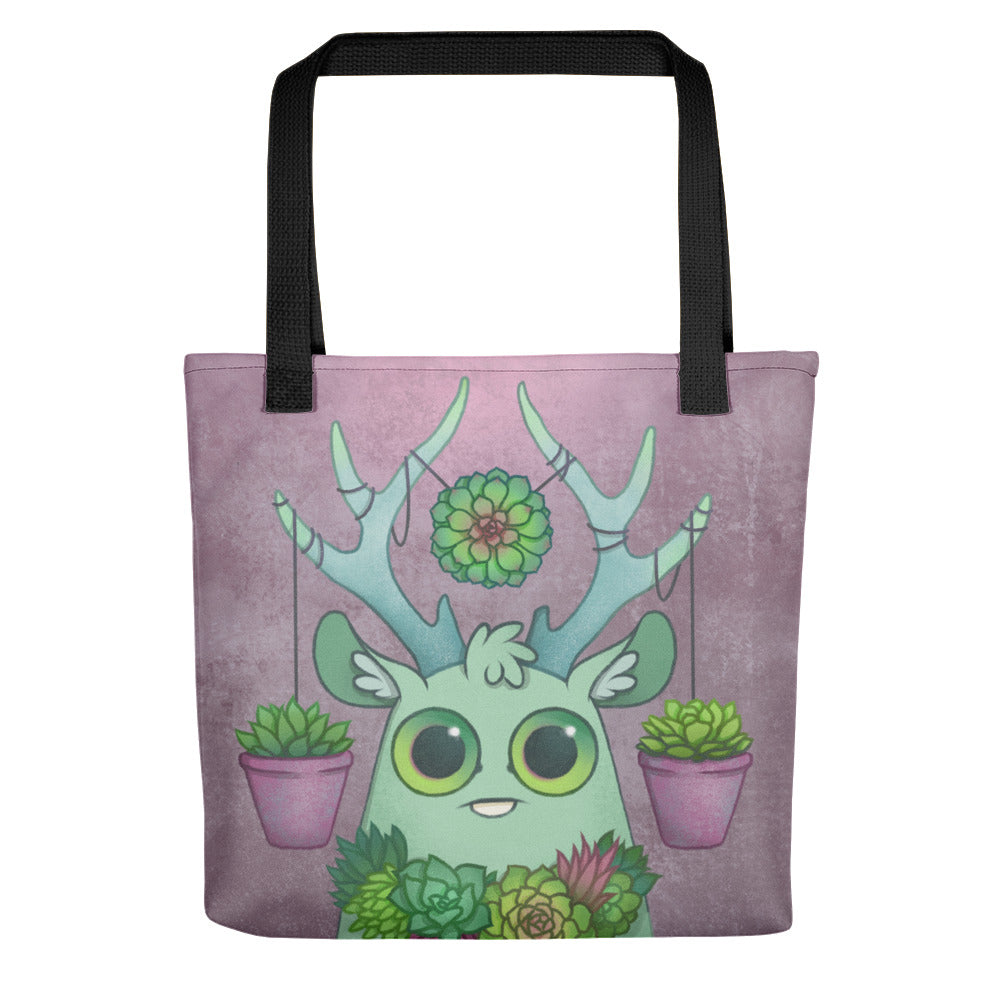 The Libra Tote from Bindlewood Shop features a cute green deer with leafy antlers, succulents on its head and chest, and two pink pots hanging from its antlers—all set against a textured purple background.