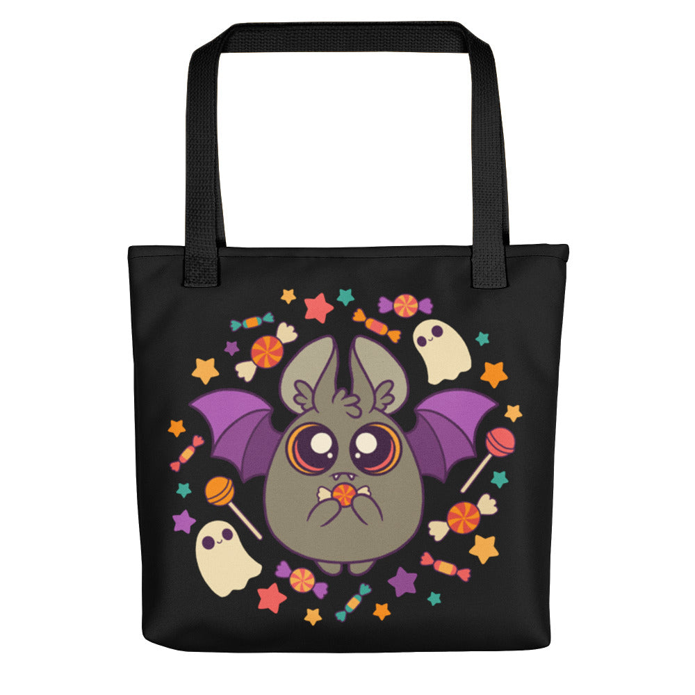 The Candy Bat Tote by Bindlewood Shop is a black, durable bag featuring a cute bat with purple wings, candy, stars, and ghosts—a festive Halloween accessory perfect for trick-or-treating and collecting sweets.