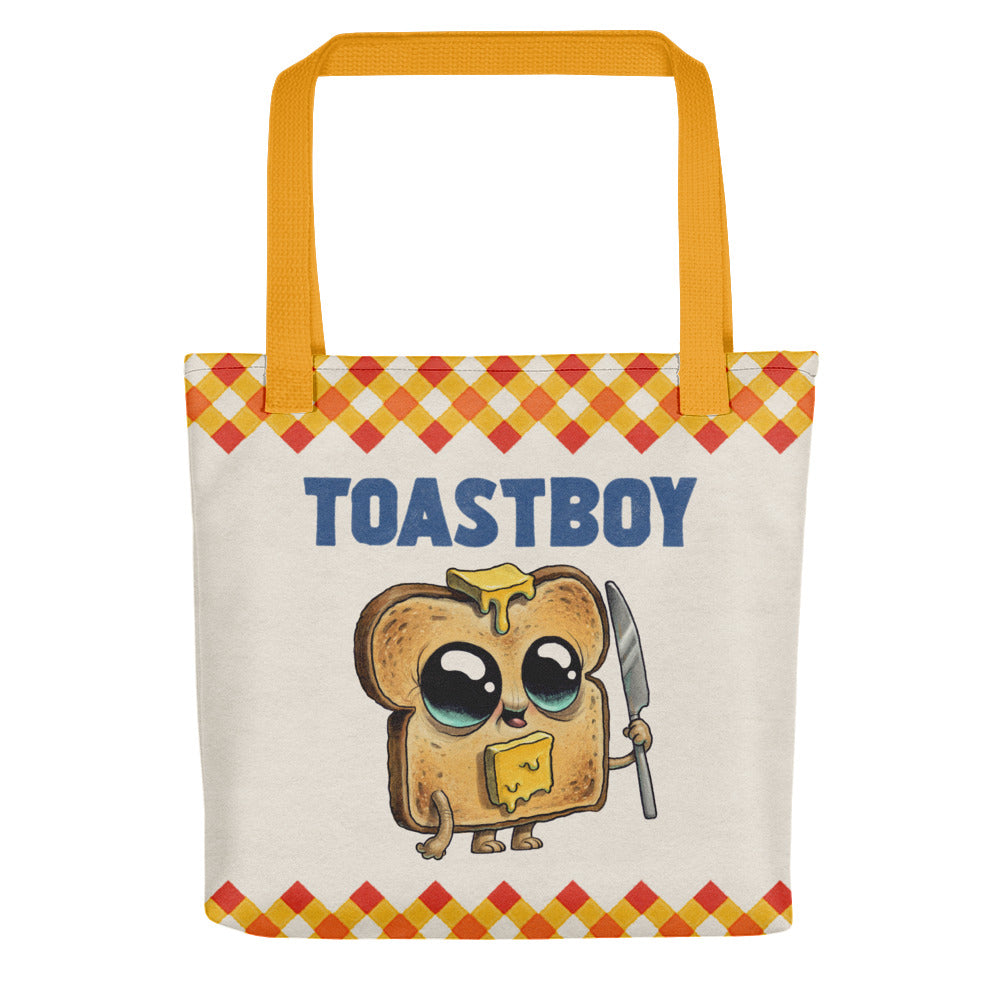 The Toastboy Tote by Bindlewood Shop features orange handles, a cartoon toast with big eyes, a knife, butter on its head, "TOASTBOY" text, and red-yellow checkered borders for a fun vintage look.