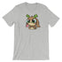 The Cactalope Tee from Bindlewood Shop features an illustrated design by Chris Ryniak, depicting a gray T-shirt with a brown creature that has large green eyes, small antlers, and a long pink tongue. Its playful expression adds a whimsical touch, while the gender-neutral fit provides comfort for everyone.