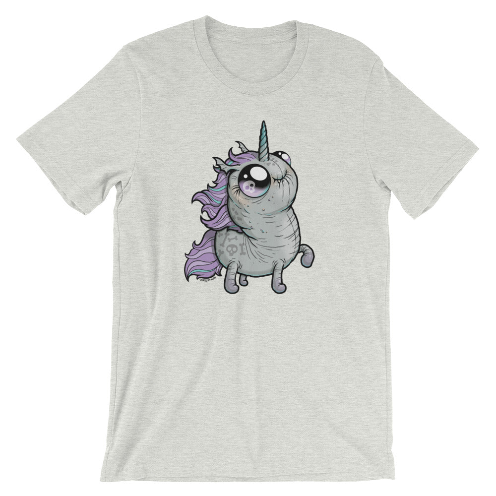 A light gray T-shirt featuring a cartoon-style illustration of a plump, whimsical unicorn. The unicorn has a light gray body, vibrant purple mane and tail, and a small horn on its head. Its big, expressive eyes and blushing cheeks add to its cute appearance. This Goth Ponycorn Tee by Bindlewood Shop boasts high-quality fabric in a gender-neutral fit.
