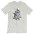 A light gray T-shirt featuring a cartoon-style illustration of a plump, whimsical unicorn. The unicorn has a light gray body, vibrant purple mane and tail, and a small horn on its head. Its big, expressive eyes and blushing cheeks add to its cute appearance. This Goth Ponycorn Tee by Bindlewood Shop boasts high-quality fabric in a gender-neutral fit.