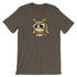 The Cactalope Tee from Bindlewood Shop is a brown T-shirt showcasing an adorable cartoon Cactalope with big green eyes, brown ears, and tiny green antlers. Inspired by Chris Ryniak, this charming creature has a playful expression and is depicted sitting with its front paws visible. The shirt provides a comfortable, gender-neutral fit.