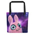 A Pipsqueak Galaxy Tote made from weather-resistant spun polyester featuring a whimsical illustration of a cartoon-like pink creature with large, expressive blue eyes set against a vibrant cosmic starfield background from Bindlewood Shop.