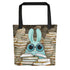 The So Many Books Tote by Bindlewood Shop features a wide-eyed blue rabbit with glasses among book stacks, reading an open book. With black handles, it’s the perfect charming gift for any book lover.