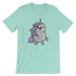 The Goth Ponycorn Tee from Bindlewood Shop is a light green T-shirt featuring a chubby, cute unicorn illustration at the center, made from high-quality fabric. The unicorn has a purple mane, a sparkling horn, and big, expressive eyes, giving it a whimsical and endearing appearance. The shirt boasts short sleeves and a gender-neutral fit with a round neckline.