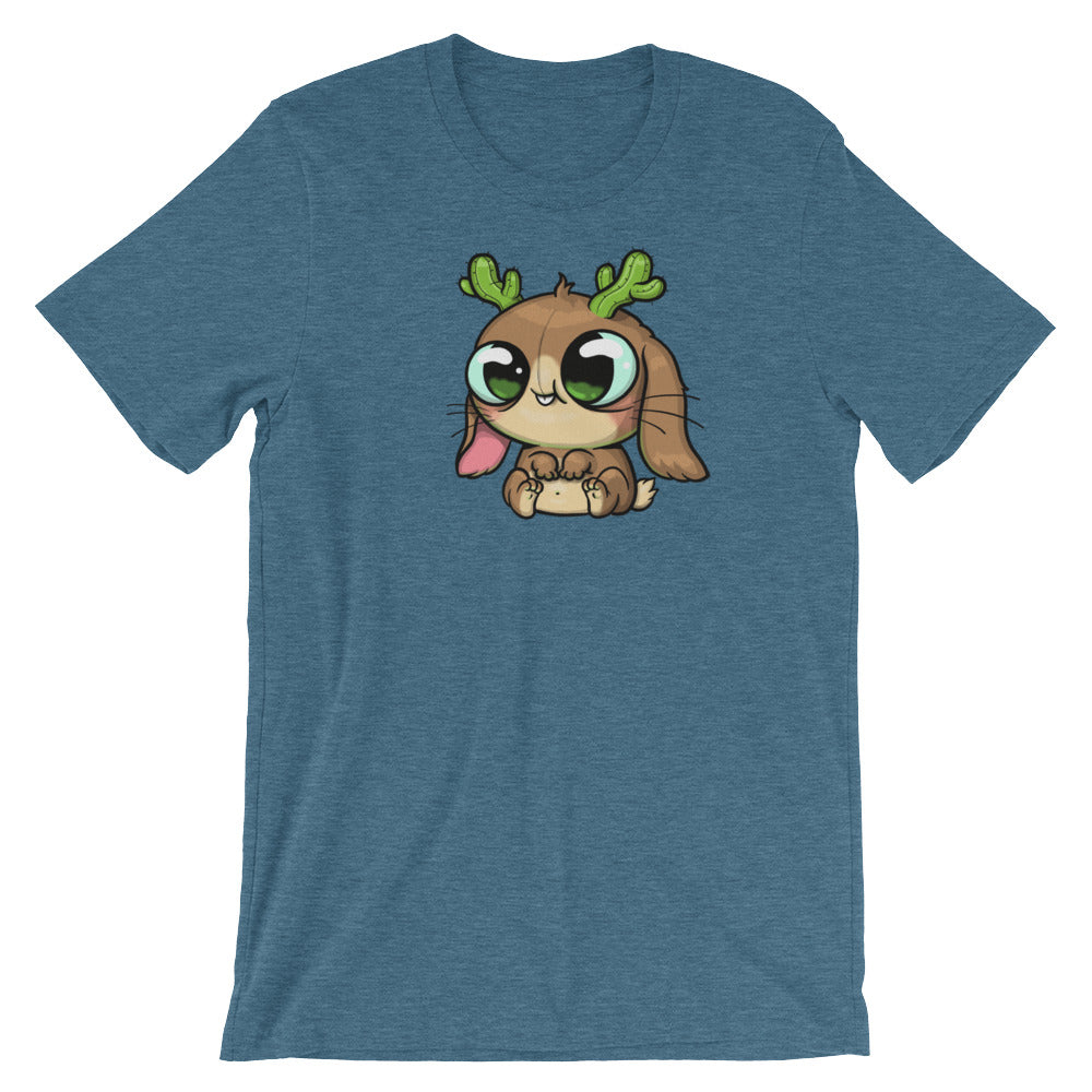 This is the Cactalope Tee from Bindlewood Shop, a blue t-shirt showcasing a charming cartoon character in Chris Ryniak's whimsical style. The character, with its big eyes, brown fur, green antlers, and a small pink tongue sticking out as it sits down, resembles a Cactalope. This tee is designed for a comfortable gender-neutral fit.