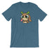 This is the Cactalope Tee from Bindlewood Shop, a blue t-shirt showcasing a charming cartoon character in Chris Ryniak's whimsical style. The character, with its big eyes, brown fur, green antlers, and a small pink tongue sticking out as it sits down, resembles a Cactalope. This tee is designed for a comfortable gender-neutral fit.