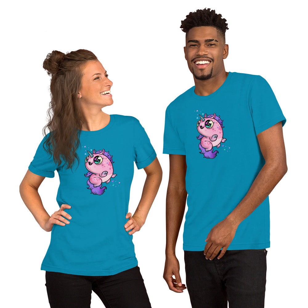 A woman and a man are smiling while wearing matching blue T-shirts featuring Chris Ryniak's colorful Flooficorn. The unicorn is predominantly pink with purple accents and is surrounded by small stars and sparkles. The woman has her hair styled in a bun, and the man has short hair. They are wearing the Floofy Unicorn Magic Tee from Bindlewood Shop.