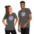 A woman and a man stand smiling, both wearing the Pastel Candy Bat Tee from Bindlewood Shop. The dark grey t-shirts feature a vibrant purple bat surrounded by stars and hearts. Designed to fit any gender comfortably with pre-shrunk fabric, they strike a relaxed pose with hands on hips, facing each other against a plain white background.