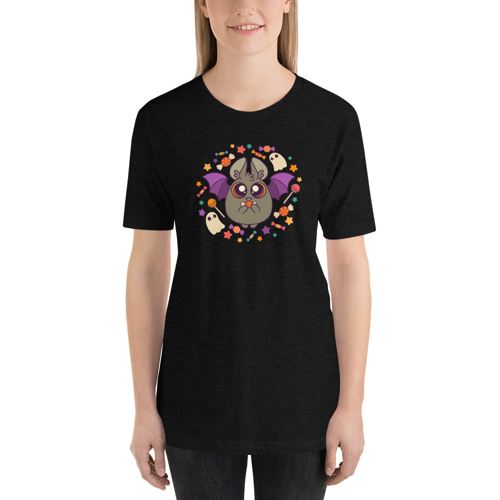 A person with long hair is wearing the Candy Bat Tee by Bindlewood Shop, which showcases a cute bat graphic in the center, surrounded by small flowers and two small ghost figures, perfectly capturing the Halloween spirit. This printed-to-order shirt features a gender-neutral fit. They are standing against a plain background and smiling.
