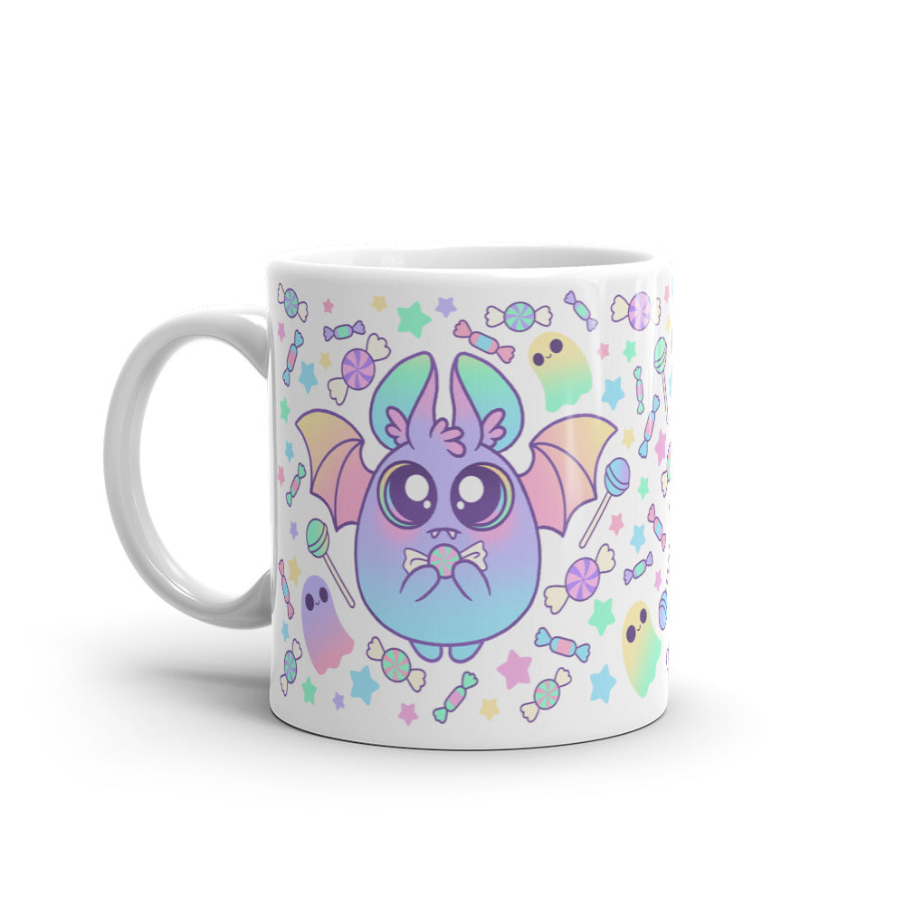 Introducing the Pastel Candy Bat Mug by Bindlewood Shop: a white ceramic mug adorned with a playful design that showcases an adorable, chubby bat with pastel wings. The bat is surrounded by stars, candies, and ghost-like figures in soft pastel hues. With its large eyes and small smile, this whimsical mug offers a delightful and imaginative touch. Plus, it's microwave and dishwasher safe for your convenience.