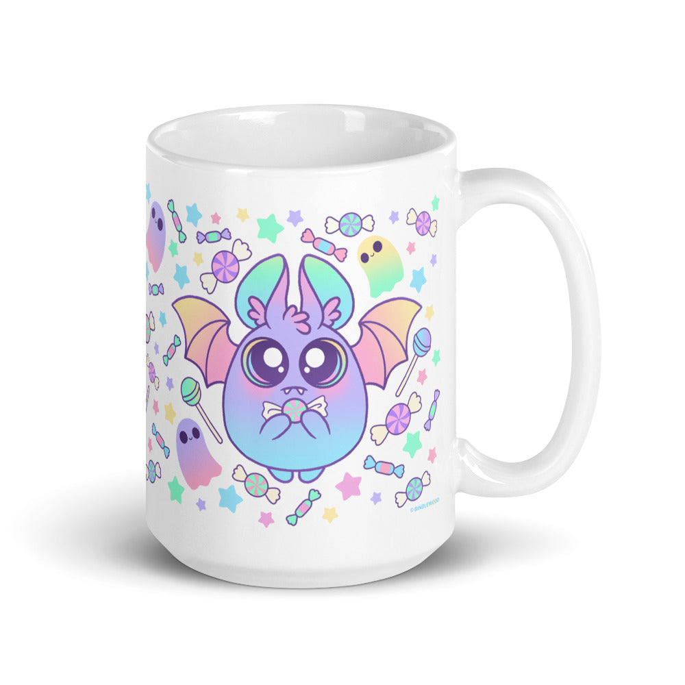 Introducing the Bindlewood Shop's Pastel Candy Bat Mug: a whimsical white ceramic mug adorned with an adorable pastel bat with big eyes and rainbow-colored wings, surrounded by colorful candies, stars, and ghost doodles. The playful design radiates a light, festive Halloween theme and ensures both microwave and dishwasher safety for your convenience.